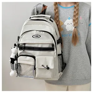 Dettaglio zaino in nylon bianco con tasche multiple, zip nere e ciondolo a panda