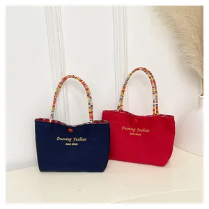 Dettaglio di borse tote in tela con manici in corda intrecciata colorata e chiusura a bottone