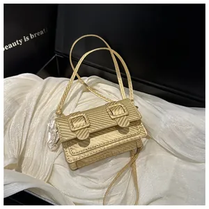 Détail d'un mini sac doré à texture carbone présenté dans un coffret cadeau noir chic