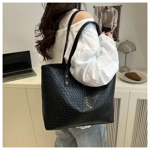 Detailed view of black woven leather tote bag texture and straps on model shoulder