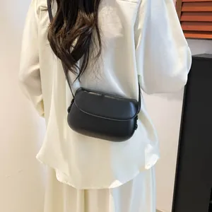 Rear view of model wearing a black retro saddle crossbody bag with a curved flap design