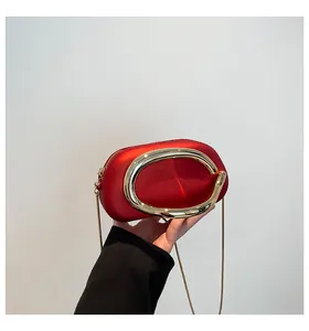 Détail du sac rouge avec un grand anneau en métal doré et une bandoulière en chaîne dorée