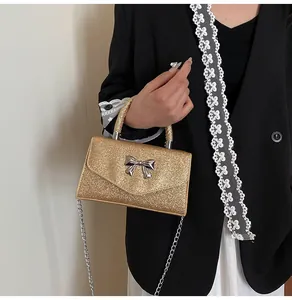 Macro detail of gold glitter trapezoid handbag with silver bow and chain strap