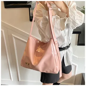 Detail of a pink glossy patent leather tote bag with an adjustable strap and metal logo