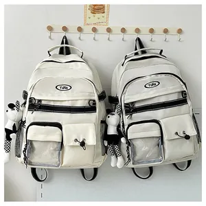 Dettaglio dello zaino panna con ciondolo panda di peluche e tasche multiple