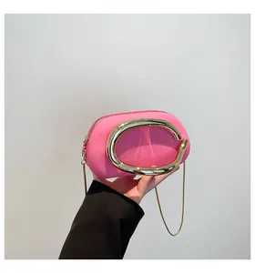 Détail d'un sac bandoulière fuchsia avec poignée anneau doré et chaîne serpent
