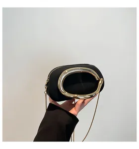 Gros plan sur la pochette ovale noire mate avec grand anneau en métal doré et chaîne