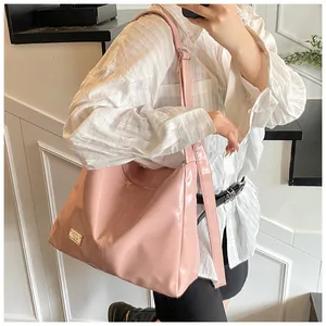 Detail of pink glossy leather shoulder bag with adjustable strap and gold metal plaque