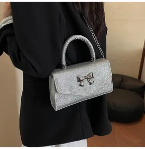 Close-up of silver glitter crossbody bag with bow detail and metal chain strap