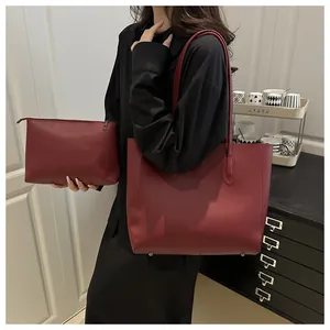 Detail view of burgundy PU leather tote and matching clutch set with minimalist stitching