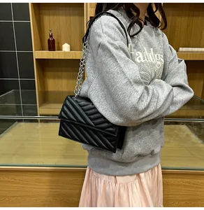 Detail einer schwarzen Stepptasche mit V-Muster, Kette und silbernem Schultergurt