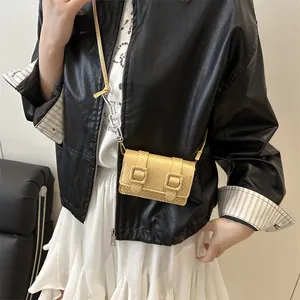 Mini sac bandoulière doré avec texture carbone et chaîne acrylique porté par un mannequin