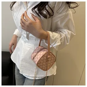 Sac bandoulière cylindrique rose avec imprimé lettres et chaîne dorée sur chemise blanche