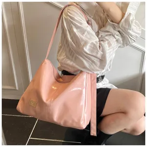 Detail of pink glossy patent leather hobo bag with a luxury gold-tone logo plaque