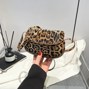 Detail of trendy leopard print saddle bag with brown trim and adjustable strap strap