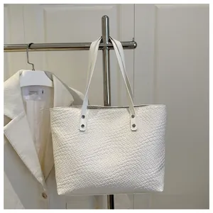 Close-up of white woven tote bag with silver rivets and elegant braided texture