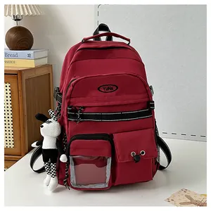 Dettaglio dello zaino rosso scuro con tasche multiple e un ciondolo a forma di coniglio