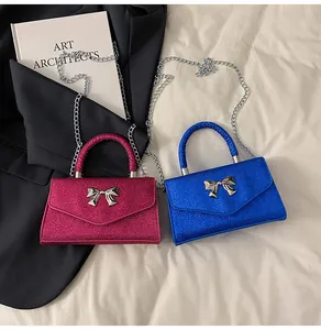 Close-up of glitter mini flap bags in fuchsia and royal blue with metal bow clasps