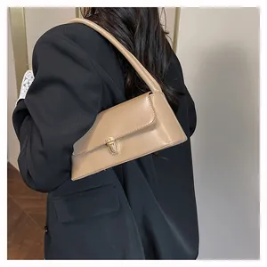 Detail of khaki baguette bag with gold metal buckle on shoulder of a black blazer