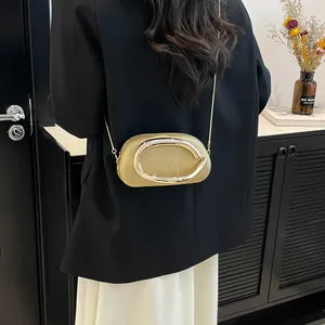 Sac bandoulière minimaliste kaki avec boucle ovale porté par un mannequin chic