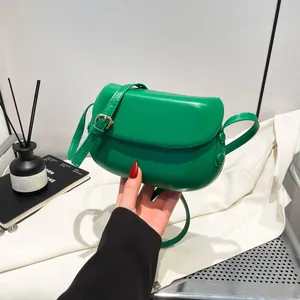 Detail of minimalist green leather saddle bag with adjustable strap and metal buckle