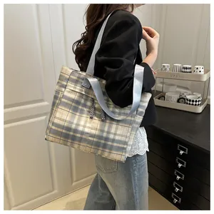 Detail of plaid tote bag featuring blue straps and drawstring on a grid pattern