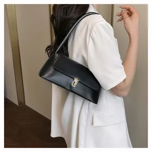 Detail of a black matte leather baguette bag with metal buckle on a model's shoulder