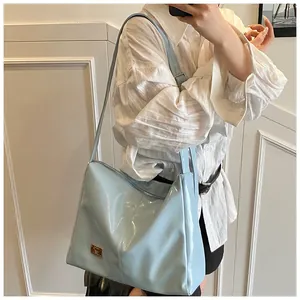 Detail of light blue glossy crossbody bag showing metallic gold logo and sleek texture