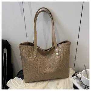 Detail of woven texture on beige tote bag with silver rivets and long shoulder straps