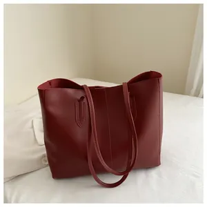 Detailed view of burgundy faux leather tote bag with vertical stitching and double handles