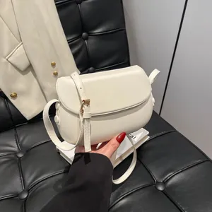 Detail view of cream saddle bag with smooth matte leather texture and gold hardware