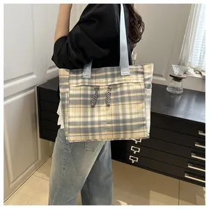Detail of plaid tote bag featuring front pocket and woven zipper pull accents
