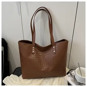 Detail of dark brown woven texture tote bag on white fabric with minimalist decor