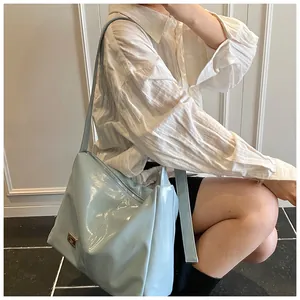 Detail of light blue glossy hobo bag with silver zipper and metallic logo plate