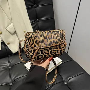 Detailed close-up of leopard print saddle bag with adjustable strap and flap closure