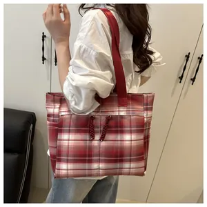 Detail of red and white plaid tote bag featuring front pocket and knotted rope accent