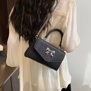 Elegant black glitter crossbody bag with silver bow accent and woven top handle