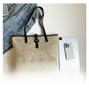 Dettaglio borsa tote in paglia intrecciata con spalline in pelle nera e fibbia argento