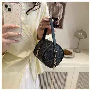 Détail d'un mini sac cylindre noir avec motif M et bandoulière chaîne dorée