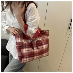 Spacious red checkered fabric tote bag with tassel zippers shown on model in modern room