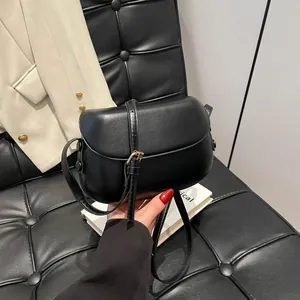 Detail of black leather saddle bag featuring a gold buckle and adjustable strap