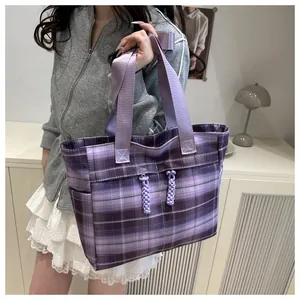 Lifestyle shot of a purple plaid tote bag with wide straps and woven rope zip pullers