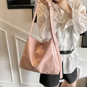 Pink glossy patent leather hobo bag with adjustable wide strap and gold logo plate