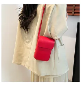 Minimalist red crossbody phone bag with adjustable strap worn on cream outfit