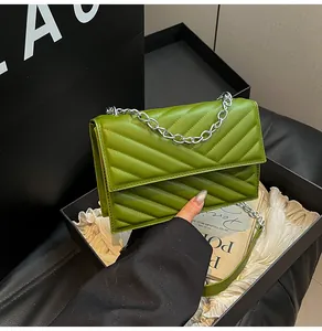 Detailansicht der grünen gesteppten Handtasche mit Silberkette auf Geschenkbox