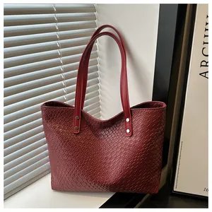 Detail view of deep red woven tote bag with smooth leather straps and silver metal rivets