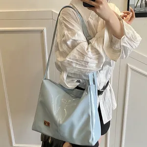 Minimalist light blue patent leather shoulder bag with glossy finish and metal logo plate