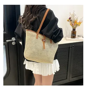 Dettaglio della borsa tote in paglia intrecciata con spalline in pelle marrone