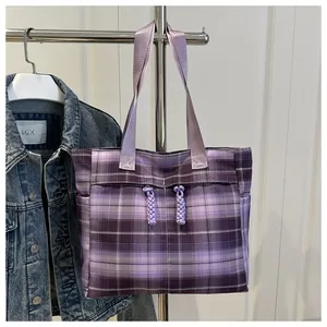 Detailed texture of purple plaid canvas tote bag with woven zipper accents and fabric handles