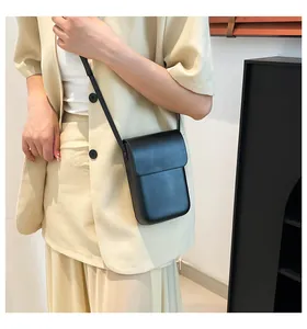 Minimalist black matte leather phone crossbody bag styled on a beige professional outfit